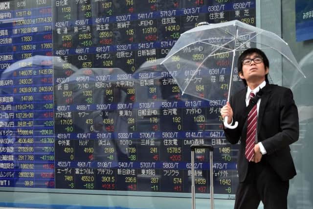 A businessman shelters from the rain in Tokyo. Many economies across the globe are doing something similar, weathering the storm consuming the Chinese markets. Picture: Getty Images