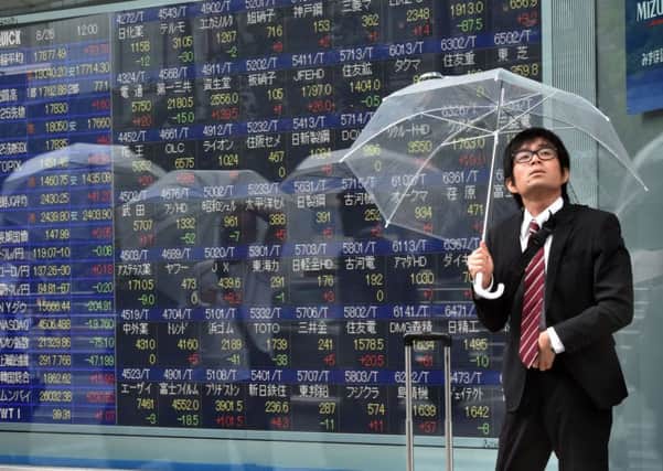 A businessman shelters from the rain in Tokyo. Many economies across the globe are doing something similar, weathering the storm consuming the Chinese markets. Picture: Getty Images