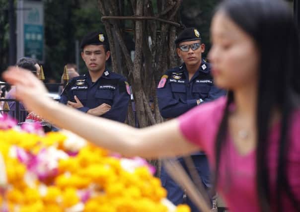 Security officers stand watch as a visitor makes an offering at the Erawan Shrine. Picture: AP