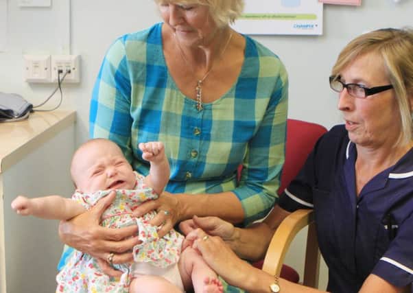 Lifelong meningitis campaigner Dr Jane Wells holds her granddaughter Daisy Wells as she gets the new vaccine. Picture: PA