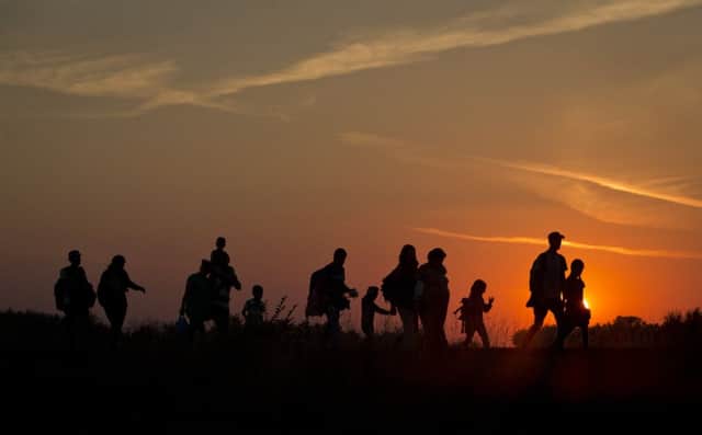 Refugees from the Middle East are silhouetted against the setting sun in Serbia as they walk along rail tracks in Roszke, Hungary. Picture: AP