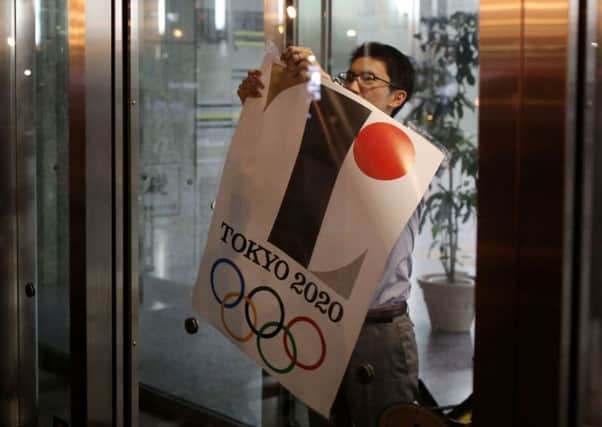 An employee removes a Tokyo 2020 Olympic poster showing the copied logo. Picture: Getty