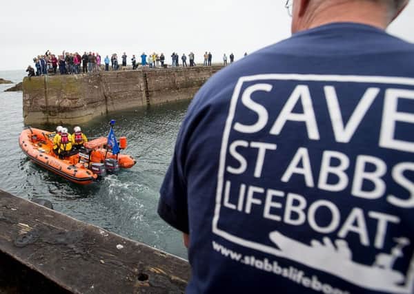 The last launch of the lifeboat is watched by locals, one of whom wears a protest T-shirt. The RNLI says that the station is no longer needed. Picture: Wullie Marr