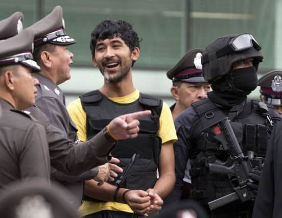 Police officers joke with key suspect Yusufu Mierili as he rectraces his alleged steps in last months Bangkok bombing. Picture: AP