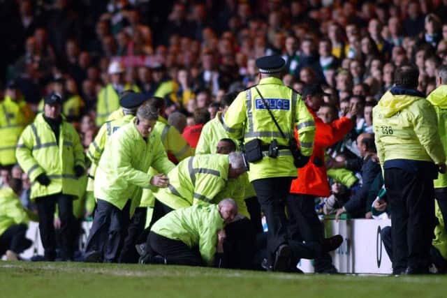Police and stewards restrain a Celtic fan after Diouf spat at a Hoops supporter. Picture: PA
