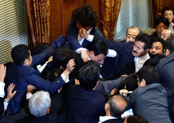 Japanese ruling and opposition politicians scuffle at the upper houses ad hoc committee session for controversial security bills yesterday. Picture: AFP/Getty