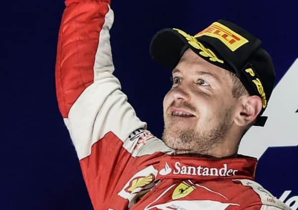 Sebastian Vettel stands aloft the podium to celebrate his victory. Picture: AFP/Getty