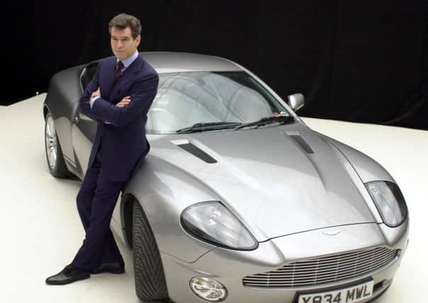 Pierce Brosnan poses in James Bond's famous tuxedo beside an Aston Martin in 2002. Picture: PA