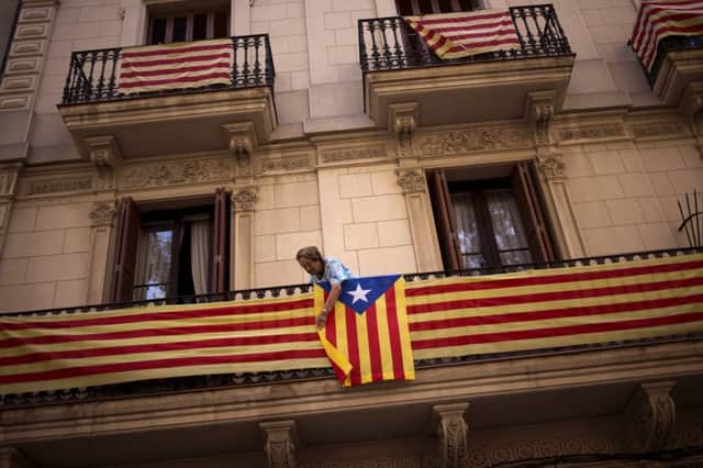 A woman attaches a pro independence flag to her balcony in Barcelona. Picture: AP