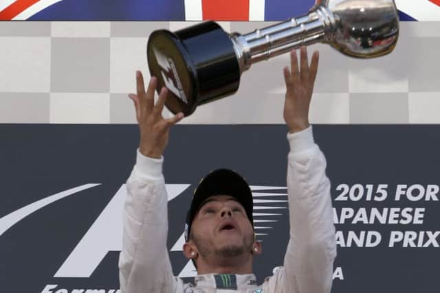 Lewis Hamilton throws his trophy into the air after cruising to victory in the Japanese Grand Prix. Picture: AP