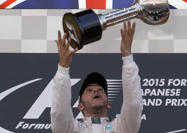Lewis Hamilton throws his trophy into the air after cruising to victory in the Japanese Grand Prix. Picture: AP