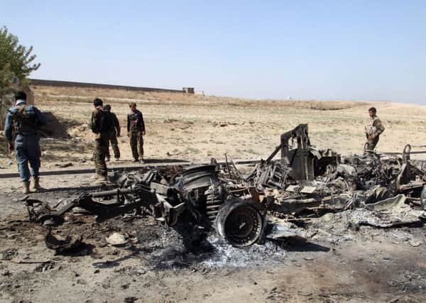 Afghan security personnel walk around a burnt out vehicle near Kunduz. Picture: AP