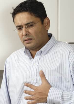 A man holds his chest in discomfort.