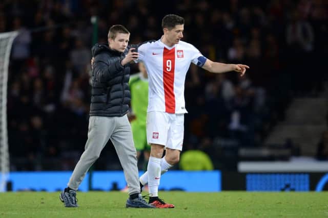 A fan invades the pitch to take a picture with Poland striker Robert Lewandowski. Picture: SNS