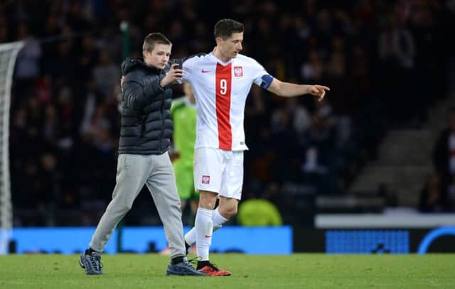 A fan invades the pitch to take a picture with Poland striker Robert Lewandowski. Picture: SNS