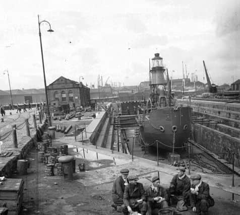 A group of workmen enjoy a lunch break in 1945. Behind them is the North Carr lightship, in dry dock for repairs.