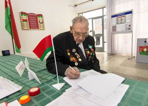 A WWII veteran signs the required documentation before casting his ballot at one of the polling stations during early voting at the Presidential election 2015 in Belarus. Picture: PA