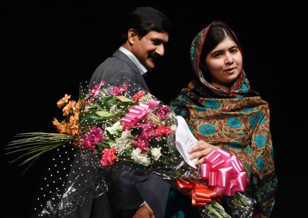 Malala Yousafzai stands with her father Ziauddin Yousafzai as she holds bouquets of flowers. Picture: Oli Scarff/Getty Images