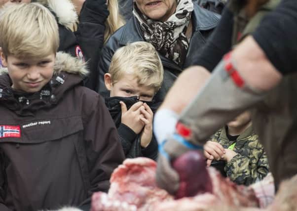 Spectators cover their faces as the animals are cut up. Picture: Getty