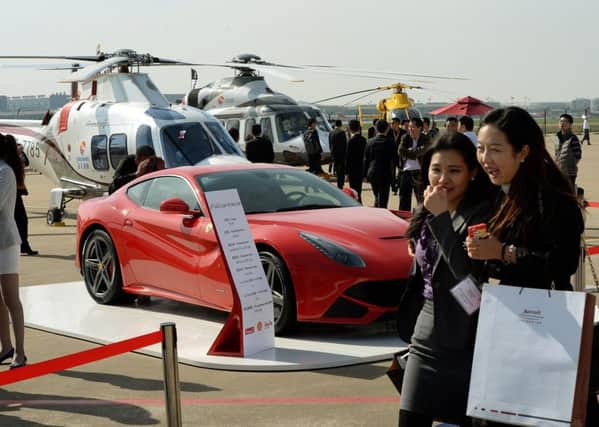 People walk past a Ferrari and helicopters at a conference in Shanghai. Picture: Getty