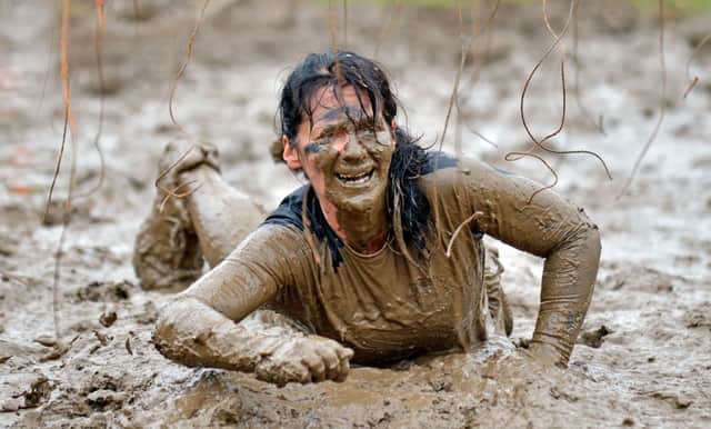 Tough Mudder competitor falls into the mud after receiving shocks from hanging elctrified wires. Picture: Phil Wilkinson.