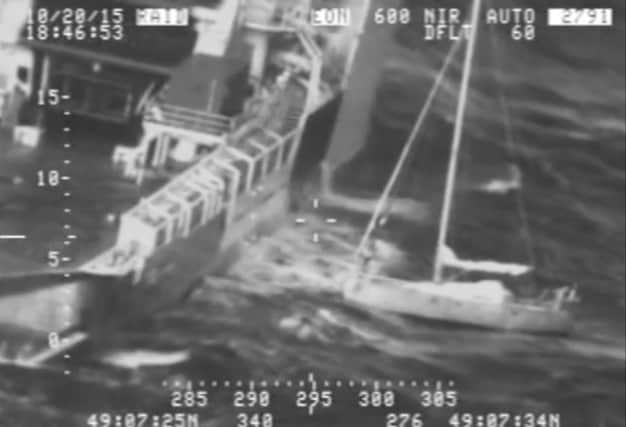 This screengrab from the US Coast Guard shows the man with his cat tucked inside his clothing, right, on his saildboat. Picture: AP