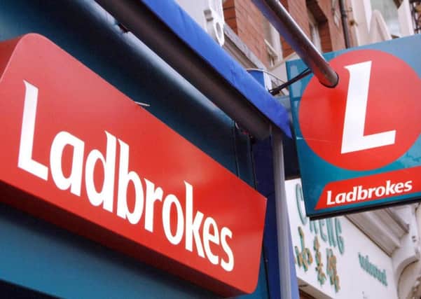 Ladbrokes said its third-quarter earnings more than halved