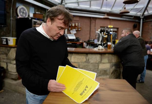 Alan Crossan, owner of the Clutha, reads the AAIB report in the recently restored bar. Picture: Hemedia