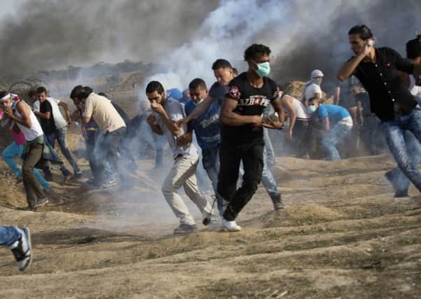 Palestinian protesters run for cover from tear gas fired by Israeli soldiers during clashes on the Israeli border with Gaza. Picture: AP