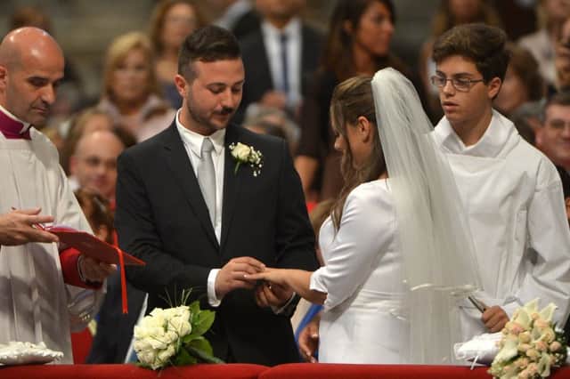 A groom and a bride exchange rings during their wedding ceremony celebrated as part of a mass by Pope Francis at St Peter's basilica on September 14, 2014 at the Vatican.  AFP PHOTO / ALBERTO PIZZOLI        (Photo credit should read ALBERTO PIZZOLI/AFP/Getty Images)