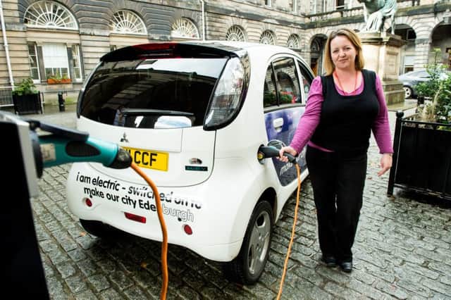 Environmental health officer Angela Davis charges a City of Edinburgh Council-owned electric car outside the City Chambers. Picture: Ian Georgeson
