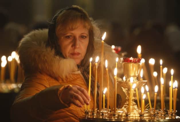 A woman lights a candle in a church in St Petersburg during a day of national mourning. Picture: AP