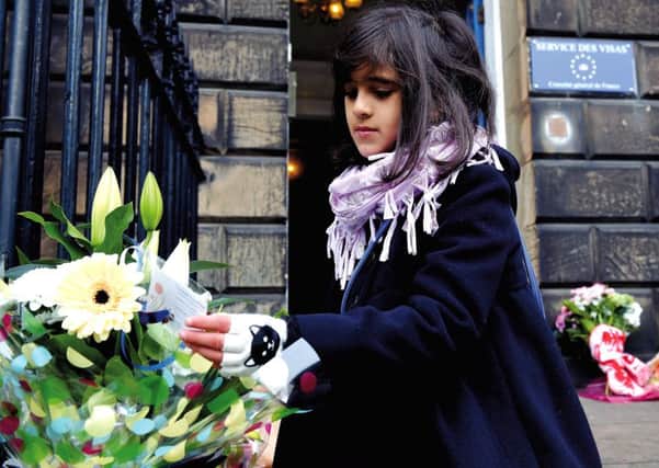 A young girl reads the messages left on the flowers outside the French Consulate

. Picture: Lisa Ferguson