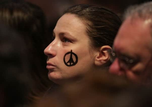 A member of the congregation with a peace symbol evoking the Eiffel Tower, at St Giles Cathedral, Edinburgh. Picture: Getty Images