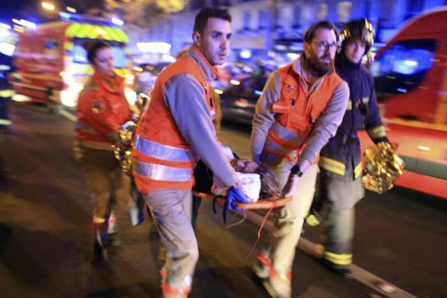 A woman is being evacuated from the Bataclan theatre after a shooting. Picture: AP