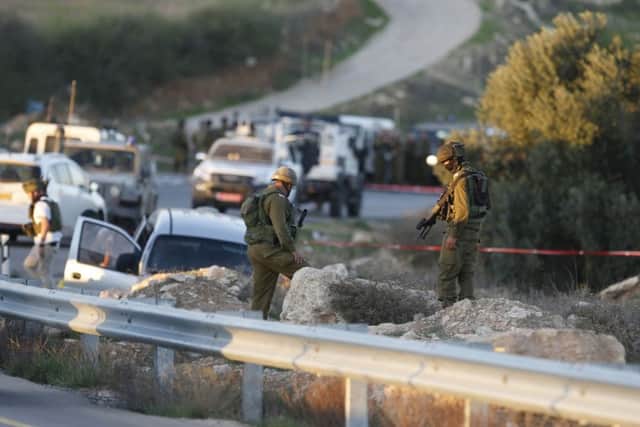 Israeli soldiers stand at the scene of the shooting of a rabbi and his son near the West Bank city of Hebron. Picture: AP