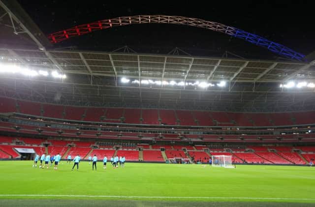 The Wembley stadium arch is illuminated in red, white, and blue lights, as France players warm up. Picture: Getty