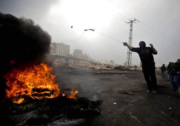 A Palestinian protester uses a sling shot to hurl stones at Israeli troops during clashes after the funerals of Ahmed Abu al-Aish, 28, and Laith Manasrah, 21, from Qalandia refugee camp. Picture: Getty