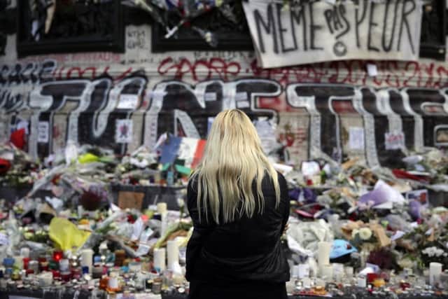 a woman stands in front of a makeshift memorial of flowers, candles and messages at the Place de la Republique square in Paris. Picture: Getty