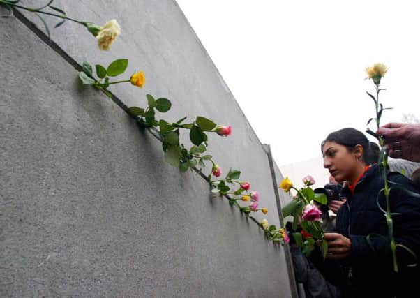 A young woman sticks a rose between concrete slabs of the former Berlin Wall at the wall memorial in the Bernauer Street in Berlin. Picture: AP
