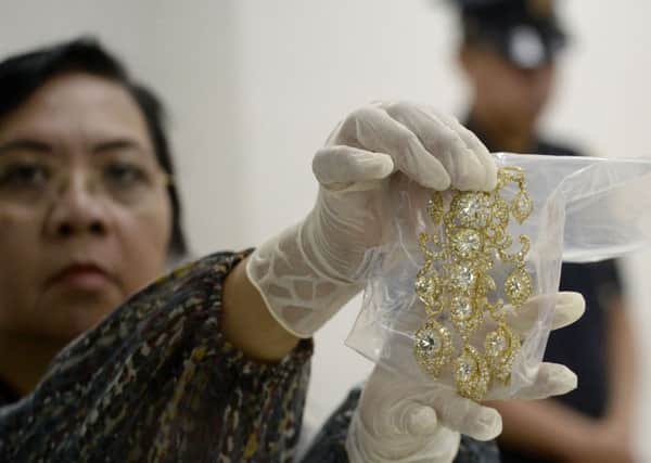 An official from the Presidential Commission on Good Government (PCGG) shows a diamond-studded piece of jewellery seized from former first lady Imelda Marcos. Picture: Getty