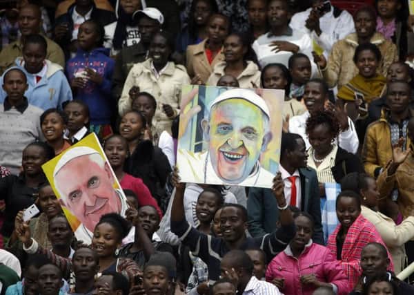 People hold up images of Pope Francis before he arrives for a meeting at Kasarani Stadium in Nairobi during his African tour. Picture: AP