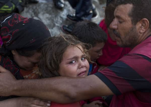 A family of Syrian refugees cry and comfort each other after a rough and scary crossing from Turkey.