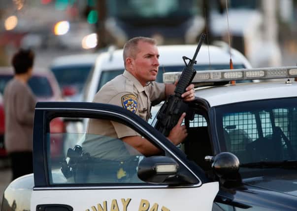 A California Highway Patrol officer stands with his weapon as authorities pursued the suspects in a shooting. Picture: Getty Images