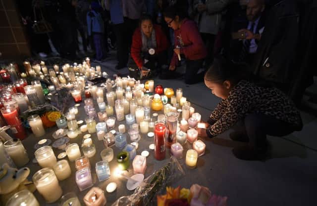 Two-year-old Trinity Cuellar places a candle during the candlelight vigil at San Manuel Stadium to honour the vicitms of the San Bernadino shootings. Picture: AP