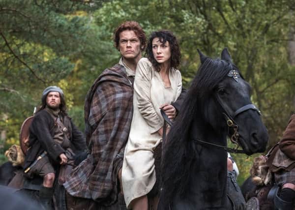 This photo released by Sony Pictures Television shows Caitriona Balfe as Claire Randall, right, and Sam Heughan as Jamie Fraser, center, and Grant O'Rourke as Rupert MacKenzie, in a scene from Starz' new TV series, "Outlander." (AP Photo/Sony Pictures Television, Ed Miller)