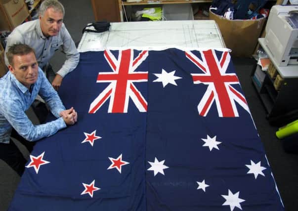 Flagmakers pose next to flags of New Zealand, left, and Australia, in their factory near Wellington, New Zealand. Picture: AP