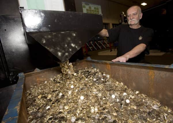 Royal Mint coin press setter John Jones handles unminted one pound coins which will become some of the final coins to be produced in its circular shape. Picture: PA