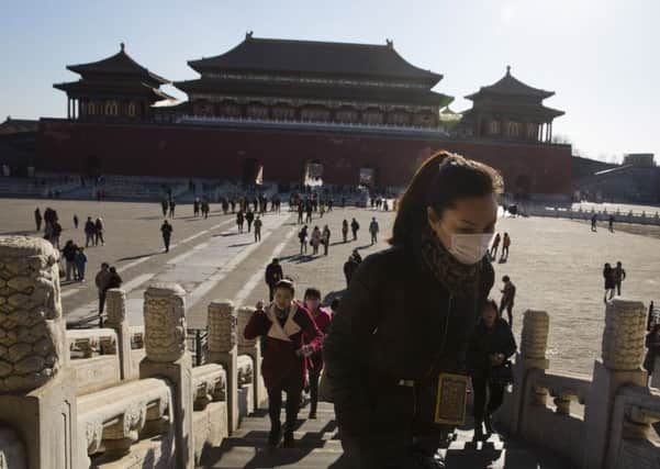 A woman wears a mask as she visits the Forbidden City in Beijing yesterday. Smog levels were expected to rise today. Picture: AP