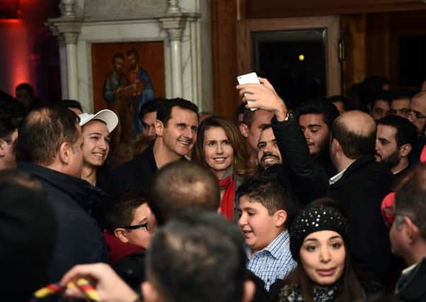 A photgraph from the official Facebook page of the Syrian presidency shows Bashar al-Assad and his wife Asma al-Assad  pose for a selfie with a Syrian man as they attend a Christmas choral presentation at the Lady of Damascus Catholic Church in the Syrian capital